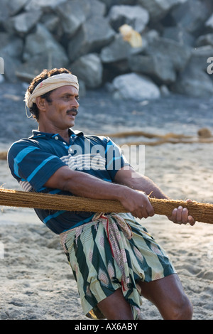 L'uomo tirando in reti da pesca sulla spiaggia di Varkala India Foto Stock