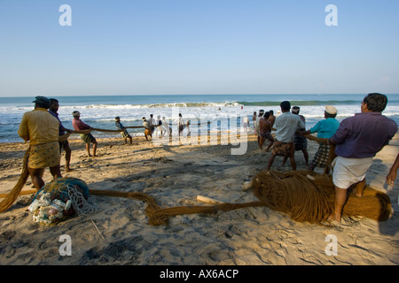 Gli uomini tirando in reti da pesca sulla spiaggia di Varkala India Foto Stock