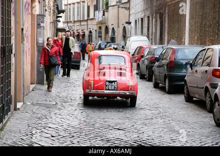 Rosso Fiat cinque cento la guida verso il basso centro di strada di ciottoli in Roma Foto Stock