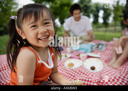 Una ragazza a pranzo da alberi con la sua famiglia Foto Stock