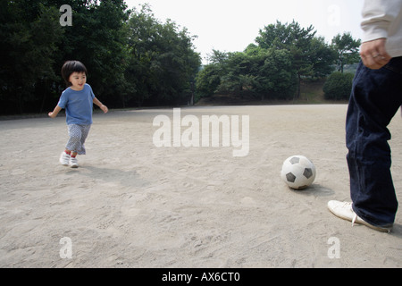 Un ragazzo giocando a calcio con suo padre Foto Stock