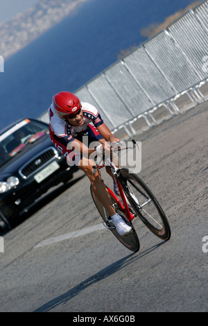 Bobby Julich USA fuori del tempo corso di prova lungo la costa di Atene road scortato dal suo team auto di supporto Foto Stock