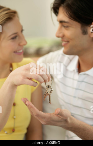 Giovane donna uomo di consegnare una chiave Foto Stock