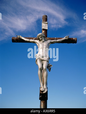 Un color argento di Gesù Cristo si blocca su un crocifisso in Nova Scotia Canada con un cielo blu in background Foto Stock