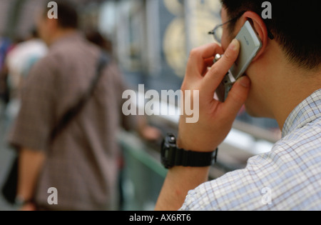 Un uomo parla su un telefono cellulare mentre si cammina per lavorare su Hong Kong Central escalator la più lunga del mondo Foto Stock