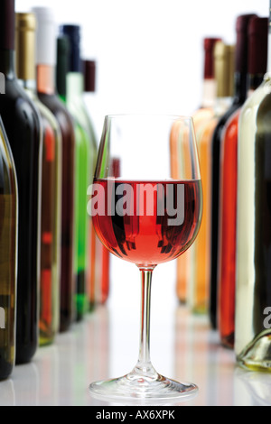 Bicchiere di vino rosso tra le bottiglie di vino, close-up Foto Stock