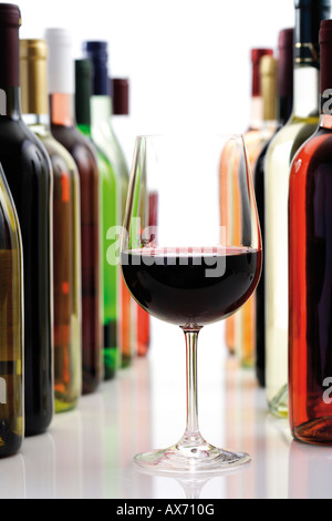 Bicchiere di vino rosso tra le bottiglie di vino, close-up Foto Stock