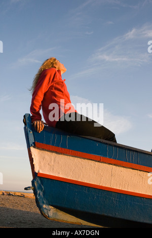 Giovane donna seduta in barca guardando il cielo Foto Stock