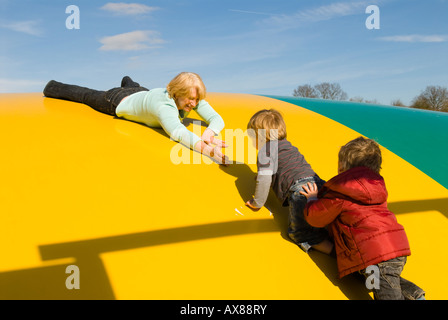 Nonna madre figlio nipote ragazzi giovani due anni e quattro anni di età i bambini sul cuscino di salto nel parco di divertimenti Foto Stock