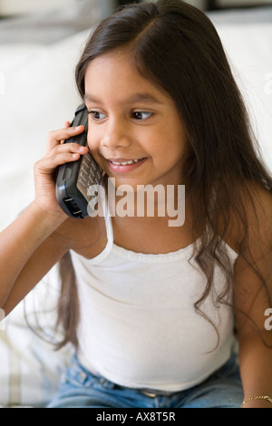 Giovane ragazza sorridente al telefono seduto che guarda lontano. Foto Stock