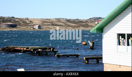 Oceano con whitecaps visto accanto a un edificio bianco con il tetto verde pier in primo piano Foto Stock