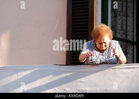 Signora anziana a guardare il mondo che passa dal balcone a castello d empuries Catalogna SPAGNA Foto Stock