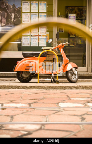 Un scooter Vespa incatenato al POST SU STRADA MILANO ITALIA Foto Stock