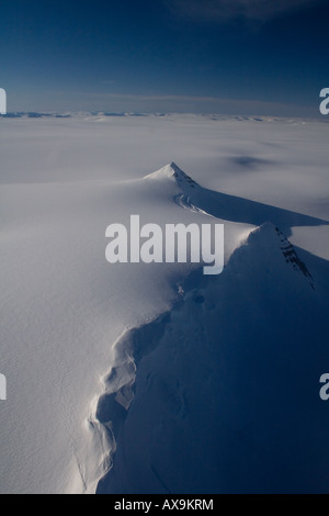 Arial vista attraverso il bordo dei ghiacciai della Groenlandia lungo un crinale montuoso coperto permanenti di ghiaccio del ghiacciaio Foto Stock