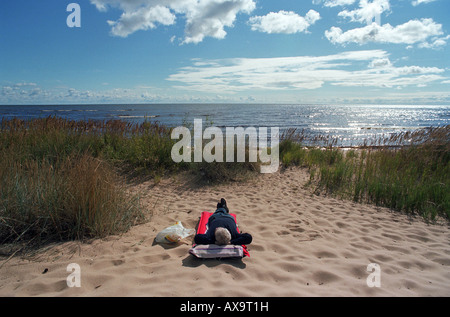 Uomo disteso su un materasso su una spiaggia sul lago Peipus in Estonia Foto Stock