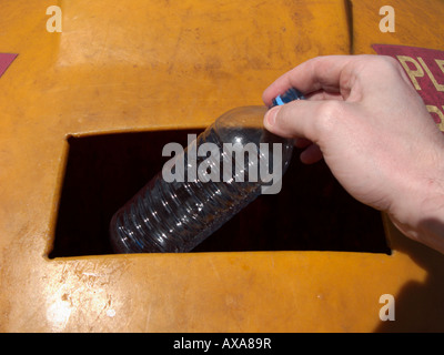 Man mano collocando un vuoto riciclabili pulire la bottiglia di plastica in un contenitore di riciclaggio al deposito di riciclaggio Foto Stock