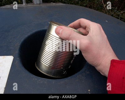 Man mano collocando un vuoto riciclabili grandi metallo pulito possibile in un contenitore di riciclaggio al deposito di riciclaggio Foto Stock