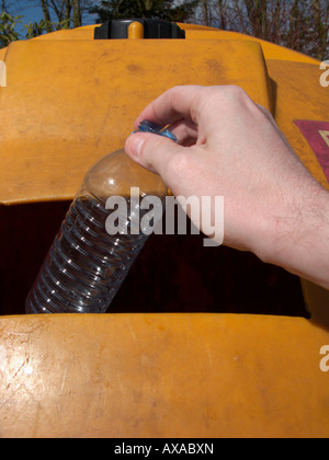 Man mano collocando un vuoto riciclabili pulire la bottiglia di plastica in un contenitore di riciclaggio al deposito di riciclaggio Foto Stock