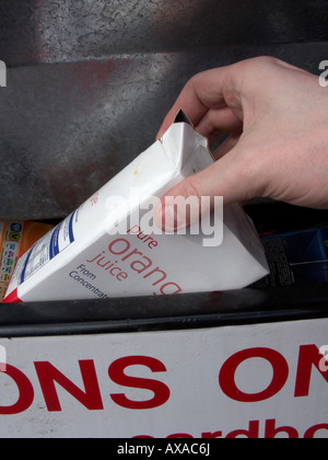 Man mano collocando un vuoto riciclabili puliti succo di frutta il contenitore in un contenitore di riciclaggio al deposito di riciclaggio Foto Stock