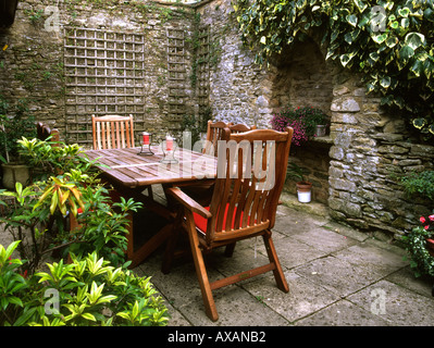 Piccolo giardino patio, mura intorno, tavoli in legno e sedie Foto Stock