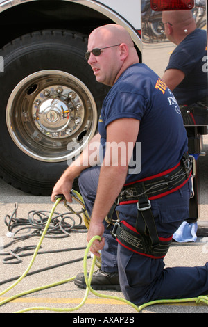 Fire Fighter knelling nella parte anteriore del carrello di tenere su le corde da un arial fune salita Foto Stock