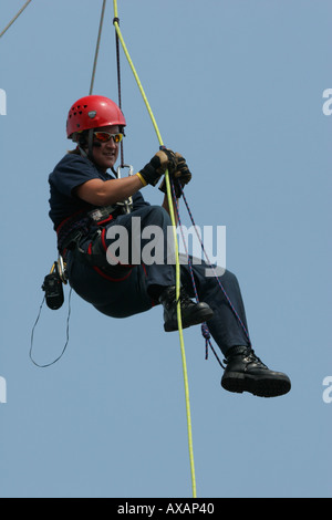 La donna pompiere salendo le corde da un arial scaletta Foto Stock