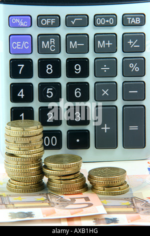 Contabilità aziendale e finanza concetti pila di monete e banconote in euro con sfondo calcolatrice Foto Stock