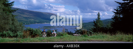 Panoramica scena estiva di due persone seduto rivolto verso il basso sul bellissimo mare e colline di Kyles of Bute, Argyll, Scozia Foto Stock