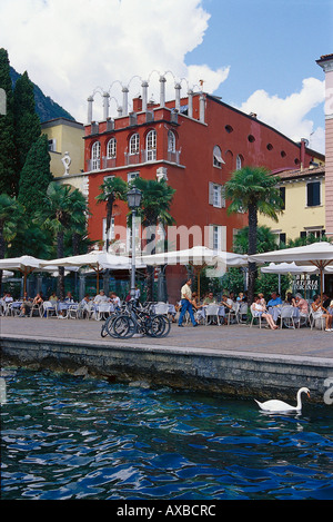 La gente seduta sotto ombrelloni presso un cafè al lungolago, Torbole, Lago di Garda, Trentino, Italia, Europa Foto Stock