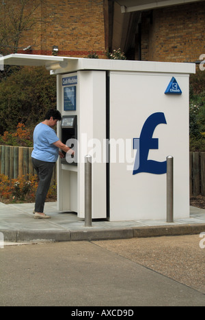 62 sessanta due anni casalinga con punto di contanti booth su Tesco di riempimento benzina piazzale della stazione Foto Stock
