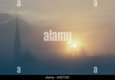 Europa Germania Baviera Oberammergau tramonto nebbia chiesa cappella Alpi bavaresi mountainssilhouette neve atmosfera meteo Foto Stock