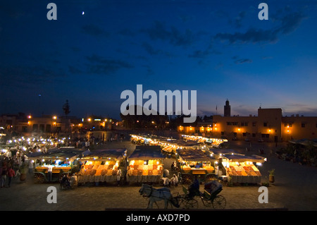 Paesaggio urbano orizzontale di Place Jemaa El Fna o Jemaa el-Fnaa o Jamaa al-fanâ a Marrakesh illuminato di notte con una carrozza trainata da cavalli o caleche. Foto Stock