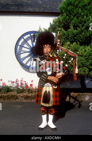 Gretna Green - Scots Piper al di fuori del vecchio famoso Fabbri Shop Foto Stock