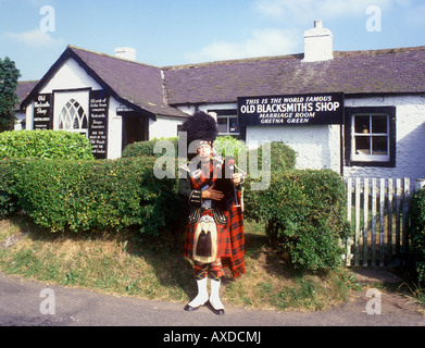 Gretna Green - Scots Piper al di fuori del vecchio famoso Fabbri Shop Foto Stock