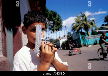 Un ragazzo nicaraguense pone con il suo giocattolo di plastica pistola proprio come ha visto sulla televisione americana. Foto Stock