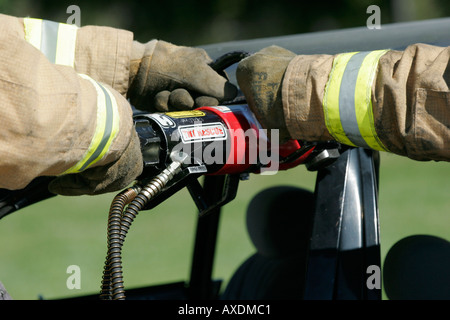 Un pompiere è utilizzando una potente macchina troncatrice per il taglio in una vettura a districarsi e il salvataggio di una vittima in un incidente di macchina incidente Foto Stock
