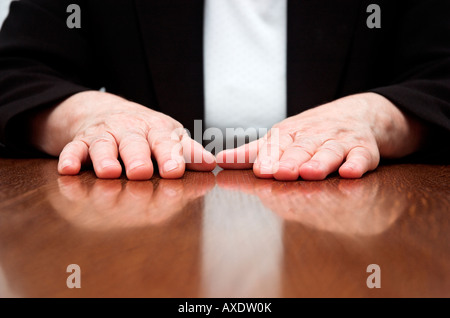 Imprenditrice seduto alla scrivania in ufficio con le mani sul tavolo Foto Stock