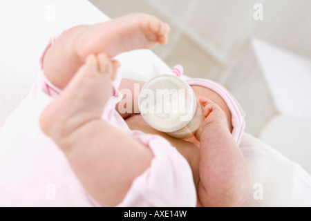 Baby girl (6-9 mesi) bere latte dalla bottiglia, ritratto Foto Stock