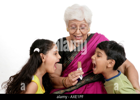 Nonna cioccolato dando ai nipoti Foto Stock