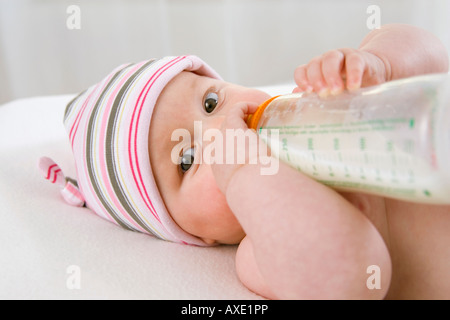 Baby boy (6-9 mesi) bere latte dalla bottiglia, ritratto Foto Stock