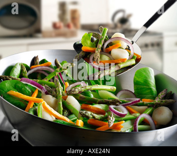 Ortaggio friggere in un wok viene agitato con gli asparagi, le cipolle rosse, germogli di fagioli, pak choi e verdure Foto Stock