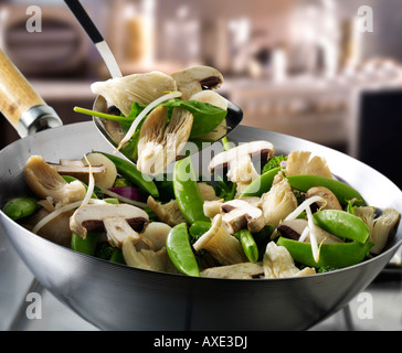 Ortaggio friggere in un wok viene agitato con Shataki e funghi Oyster, gestire tout e verdure Foto Stock