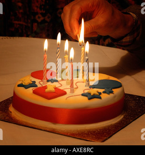 Accendendo candele su una torta di compleanno Foto Stock