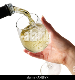 Il vino bianco che viene versato in un bicchiere da vino tenuto da una donna mano contro uno sfondo bianco Foto Stock
