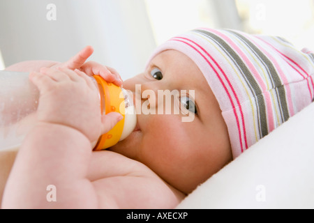 Baby boy (6-9 mesi) bere latte dalla bottiglia, ritratto Foto Stock