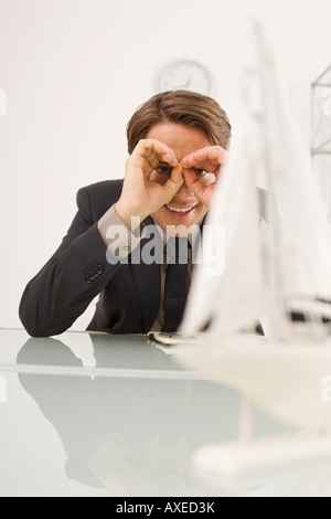 Imprenditore del peering al modello di nave, ritratto Foto Stock