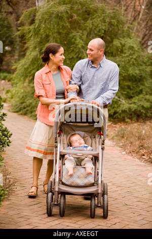 I genitori di origine ispanica spingendo il bambino nel passeggino Foto Stock