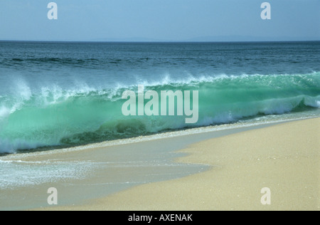 Oceani sale di potenti onde d'acqua e cappucci bianchi si infrangono sulla battigia creando uno spray nel vento e sulla spiaggia di sabbia Foto Stock