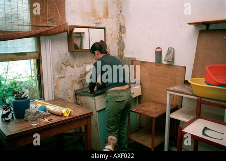 Giovane donna decorazione accovacciata nella casa in cui è cresciuta e ha vissuto per 30 anni. Foto Stock