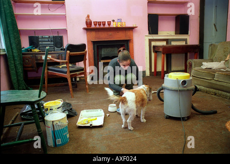 Giovane donna pulizia la sua cucina in casa accovacciata che crebbe in e ha vissuto per 30 anni. Foto Stock